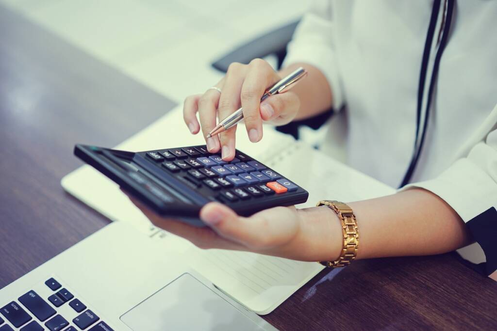 person using calculator and computer