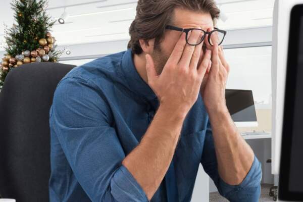 Stressed office worker with christmas tree in background